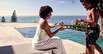 Swimming, mother and fruit to children by pool for grapes snack, hungry or healthy vitamins for energy. Holiday break, african people or happy with nutrition at resort for wellness and relax together