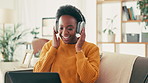 Headphones, laptop and black woman on sofa in home listening to music, radio or playlist. Dancing, computer and African female copywriter with audio tech for album with remote work online in house.