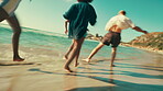 Friends, playing and running with water splash at beach for travel adventure, summer holiday and bonding together. Group, back of people and freedom by ocean for tropical vacation and weekend reunion