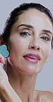 Studio, woman and face with stone for skincare, wellness and circulation for beauty treatment. Portrait, cosmetics and mature person with gua sha for transformation, dermatology and white background