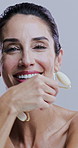 Face, jade roller and laughing with mature woman in studio for morning cosmetics or skincare routine. Funny, massage and relax with person on white background for dermatology or natural beauty