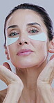 Cosmetics, woman and face with eye patches for skin hydration, rejuvenation or wrinkles reduction. Beauty, person and collagen treatment for dark circles, self care or anti aging on studio background