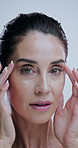 Woman, anti aging and face in studio with beauty, inspection and check for wrinkles by background. Mature person, model and portrait for cosmetics, glow and transformation for crows feet in Greece