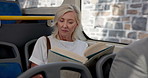 Mature woman, bus and reading with story for travel, novel or free time in public transportation. Female person, book or literature with vehicle for tourism, commute or local journey in an urban town