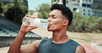 Man, fitness and drinking with water for hydration, break or rest for workout at stadium in city. Male person, athlete or runner with mineral liquid for thirst, recovery or natural sustainability