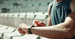 Man, hands and checking fitness with smart watch at stadium for workout app, schedule exercise or training routine. Closeup, male person or runner with wristwatch for sport feed or healthy tips