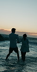 Playing, sunset or happy couple in water at sea for valentines day or love in interracial relationship. Night, splash or people bonding at beach on holiday for romantic honeymoon, vacation and date