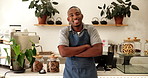 Arms crossed, face and smile with black man in coffee shop as manager or owner of small business. Happy, hospitality and welcome with barista or waiter in apron for cafe and restaurant management