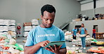 Volunteer, man and typing with tablet in warehouse for food bank, inventory management and donation stock control. Community service, person and digital app for grocery checklist and charity outreach