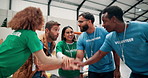 Happy people, volunteer and team with hands together for motivation or support at NGO warehouse. Excited, group or piling in huddle with unity for social responsibility, charity or community service