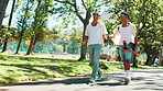 Skateboard, men and friends in park walking for bonding, social gathering and outdoor nature. Fashion, cool skaters and people on path for talking on holiday, vacation or adventure on fun weekend
