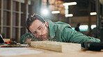 Man, carpenter and blow sawdust in factory for cleaning, design or ppe for safety with manufacturing. Person, artisan and wood for creativity, industry or process for furniture production in workshop