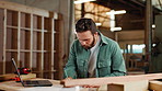 Carpentry, writing and carpenter in workshop on laptop for client orders, furniture and manufacturing. Factory, construction and man on computer for lumber, timber inventory and woodwork production