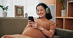Pregnant woman, relax and headphones with phone at house, streaming podcast and prenatal website. Smile, person and mobile for listening to music, pregnancy research and maternity development on sofa