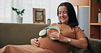 Happy, pregnant woman and relax with headphones on stomach for music, comfort or soothing on sofa at home. Female person, smile or earphones with baby belly for calming relief in maternity at house