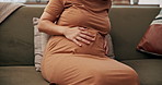 Pregnant woman, hands and stomach with ache on sofa for maternity contractions, cramps or rub at home. Closeup, female person or baby belly with pregnancy for soothing discomfort or feeling at house