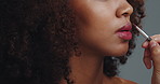 Hands, mouth and lipstick brush in studio for beauty, closeup and transformation by background. Person, model and tools for makeup, application and change with color, lips and process for cosmetics
