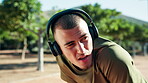 Fitness, tired and man with headphones, breathing and playlist for workout in morning or outdoor. Park, runner and person with fatigue on break, exhausted and listening to music with tech or exercise