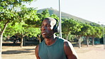 Headphones, running and black man in park for workout, wellness and fitness. Radio, podcast and African athlete with endurance training, exercise and health for cardio and jog outdoors in nature