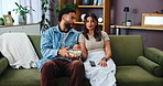 Couple, living room and watching tv with popcorn for chat, conversation or movies on sofa at home. Man, woman and streaming service with discussion, communication and eating with snack at house