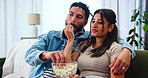Couple, living room and watching tv with popcorn for feed, laugh and comedy movies on sofa at home. Man, woman and streaming service with discussion, communication and eating with snack at house