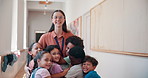Happy, hugging and face of teacher with children at school for development, bonding and learning. Care, education and female educator embrace kid students for greeting with love at elementary academy