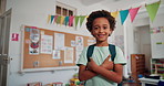 Happy, face and kid with crossed arms in classroom for learning, education or childhood development. Bag, growth and portrait of boy student with confidence for back to school at elementary academy.