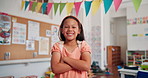Happy, face and girl kid with crossed arms in classroom for learning, education or childhood development. Scholarship, portrait and student with confidence for back to school at elementary academy.