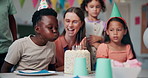 Children, clapping and blow candles for birthday party with teacher, friends and students at school. Kids, cake and happy people at celebration, congratulations and special event with class together