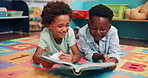 Reading, friends and kids with book in classroom for learning, development or growth. Children, relax and boy students with storytelling on floor mat for literacy knowledge at elementary school.