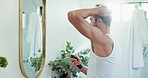 Bathroom, spray and man with deodorant, home or fresh scent for grooming in morning, mirror or smell. House, cosmetics and person with product for fragrance, perfume or prevention of order for armpit