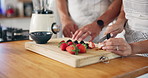 Fruit, strawberry and hands of couple in kitchen for healthy eating, nutrition and breakfast drink. Home, morning and man and woman with berries for smoothie for wellness, organic diet and vitamins