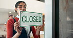 Small business, woman and closed sign by cafe door for end of service, message board and notification. Storefront, signage poster and happy barista at startup for restaurant notice and information