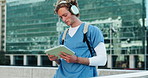 Headphones, doctor and man student with tablet in city studying for clinical exam or test. Education, technology and male healthcare intern listening to music and reading online textbook in town