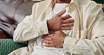 Person, hands and chest pain with heart burn, indigestion or inflammation on sofa at home. Closeup, infection or bronchitis with symptoms for muscle strain, shortness of breath or cardiac arrest
