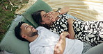 Couple, date and laugh in park with kiss, bonding and point with cloud watching. People, holding hands and outdoor for relationship development, weekend relax or smile for love and anniversary picnic