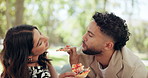 Couple, date and happy in park with lunch, bonding and laugh with feeding. People, travel and outdoor with pizza share joke for relationship development, weekend relax or smile for love or picnic