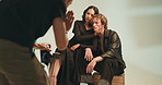 Photography, studio and photographer with couple on chair with production team for creative magazine. Fashion, equipment and gen z influencers posing on chair for portfolio photoshoot with art agency