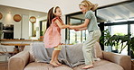 Happy girls, siblings and jumping with sofa for fun day, bonding or playful energy together at home. Excited, children or kids playing with smile or holding hands on couch for holiday or weekend