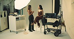 Lighting, makeup artist and photography with model on set for fashion magazine or style photoshoot. Conversation, direction or production with women behind the scenes for artistic or creative catalog