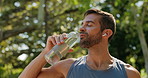 Thirsty, athlete and drinking water, man and hydration for runner with earphones, outdoor and healthy. Nature, wellness and person with liquid on break, metabolism and fitness with beverage or music