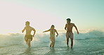 Waves, people and friends running at sea for freedom, travel or excited to splash at sunset. Outdoor, ocean water and group at beach for holiday, summer and students with energy to celebrate vacation