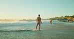 Men, friends and playful in waves, vacation and outdoor in summer, splash and running in nature. People, together and games in water, sea and ocean at beach, holiday or sunshine with tropical getaway