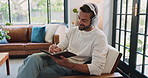 Home, writing and man with headphones, music and songwriter with inspiration in living room or creative. House, composer and person with notebook for lyrics, streaming and tech for playlist in lounge