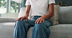 Hands, nervous and person on sofa with anxiety, stress or emotions in living room at home. Mental health, worry and shaking leg for panic attack with phobia, overthinking or fear of trauma in house.