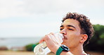 Fitness, drinking water and man with bottle in nature rest for training, workout and exercise. Sports, runner and thirsty person with liquid for wellness, health and minerals for hydration outdoors