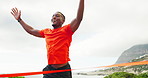 Man, running and celebrate at finish line ribbon for marathon win, fitness goal or workout achievement. African athlete, race success or competition champion excited for victory outdoor in low angle