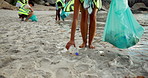 Hands, cleaning or person at beach with trash bag, teamwork or sustainability on Earth day. Climate change, legs or people at ocean with plastic collection, waste management or seaside environment