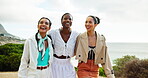 Outdoor, friends and hug with walking for holiday, travel and bonding together with conversation. Group of people, women and laughing with pointing for adventure, vacation and fashion style in nature