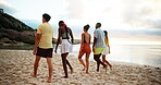 Beach, vacation and friends walking for travel, adventure and bonding together on tropical island at sunset. People, sea and group on trip outdoor at ocean for summer holiday, back view and wind